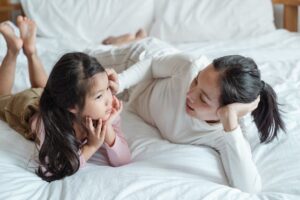 mom talks to female child in bed