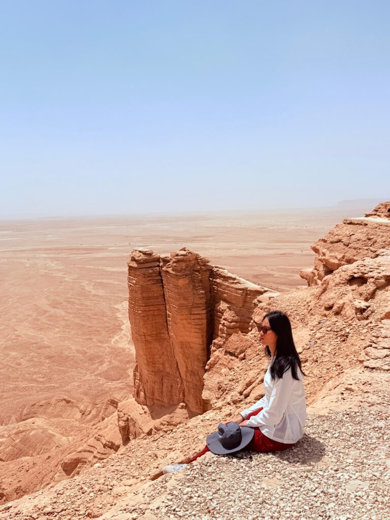 Woman sitting at the edge of a cliff during desert safari Riyadh