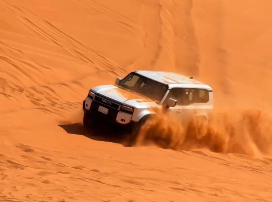 White SUV kicking up red sand while dune bashing during an adventurous desert safari Riyadh experience