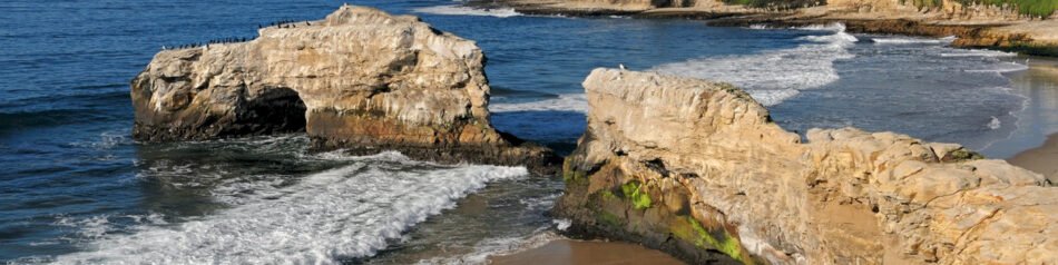 Sea stacks and a natural rock arch with cormorants at Natural Bridges State Beach near Santa Cruz, California