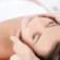 Woman relaxing with eyes closed as a therapist's hands massage her temples during a facial at St. Somewhere Spa