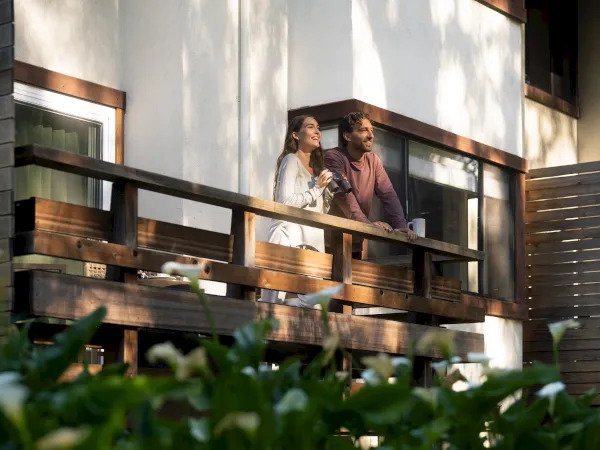 Couple enjoying morning coffee on a wooden guestroom balcony at Chaminade Resort & Spa, Santa Cruz