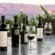 John Anthony wine bottles and glasses of red wine on an outdoor table with vineyard hills in the background