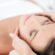 Woman relaxing with eyes closed as a therapist’s hands massage her temples during a facial at St. Somewhere Spa
