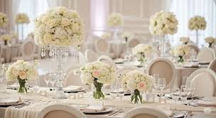 Round banquet tables with white linens and tall white rose centerpieces set for a gala reception at The Adolphus Hotel in Downtown Dallas.